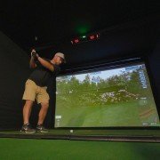 Front view of a home golfer inside a golf enclosure with a mounted Uneekor EYE XO2 system