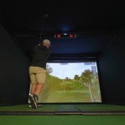 View of a home golfer inside a golf enclosure with a mounted Uneekor EYE XO2 system