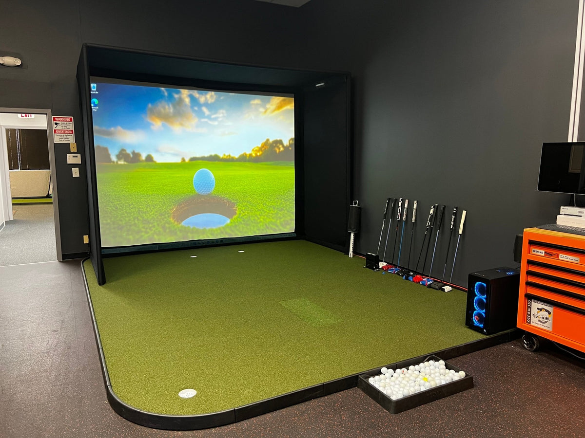 View of a Full simulator setup featuring an enclosure, screen, golf mat, and balls in a dedicated room.