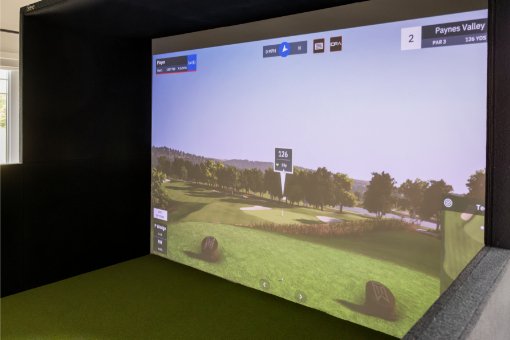 Side view of a screen displaying a golf course, surrounded by a full enclosure with half walls.