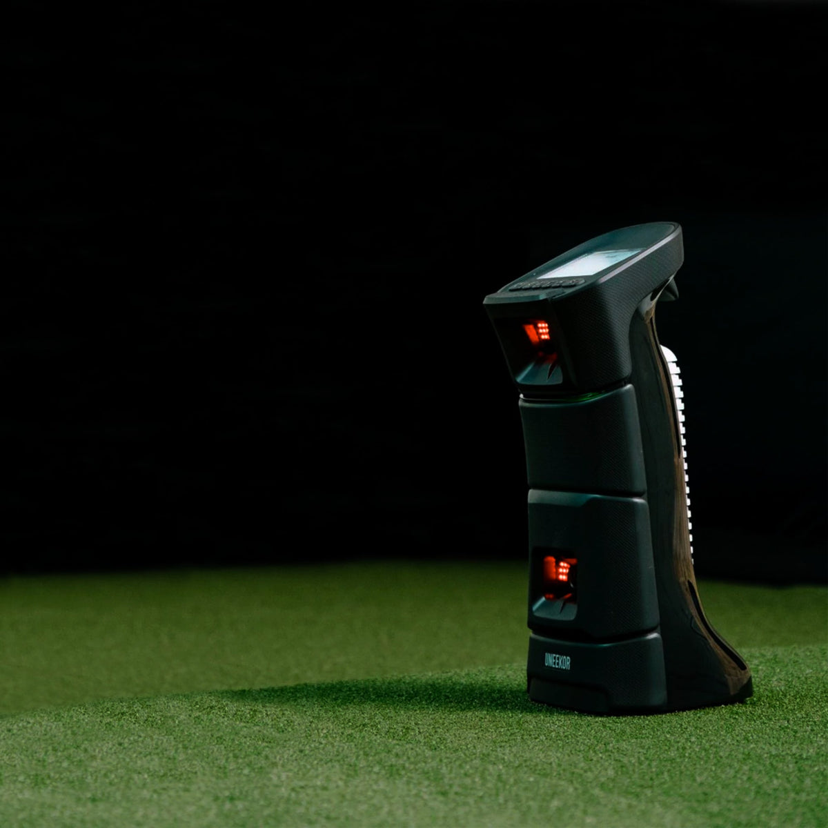 Side view of the Uneekor Eye Mini launch monitor positioned on a hitting mat