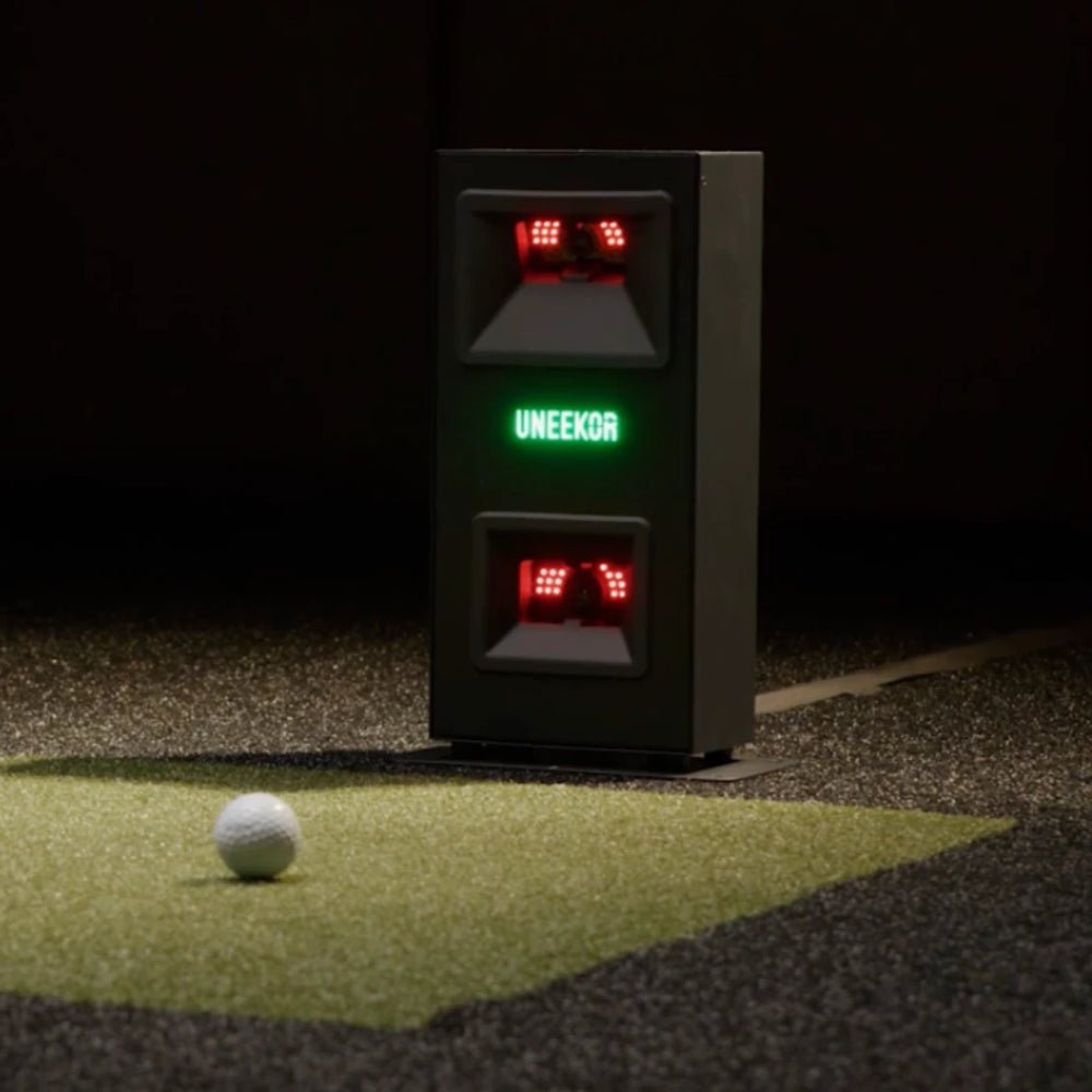 Front view of the Uneekor Eye Mini Lite lit up, with a golf ball nearby.