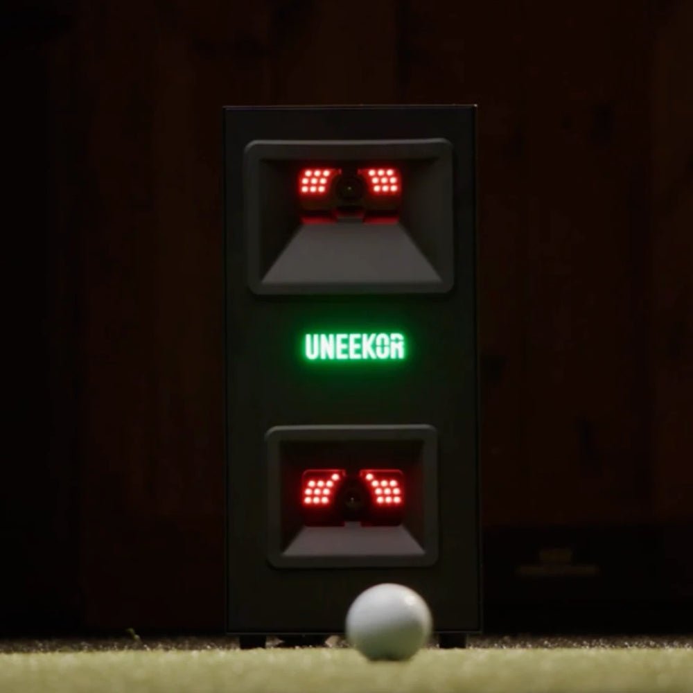 Front view of  Uneekor Eye Mini Lite lit up with a golf ball in front of it