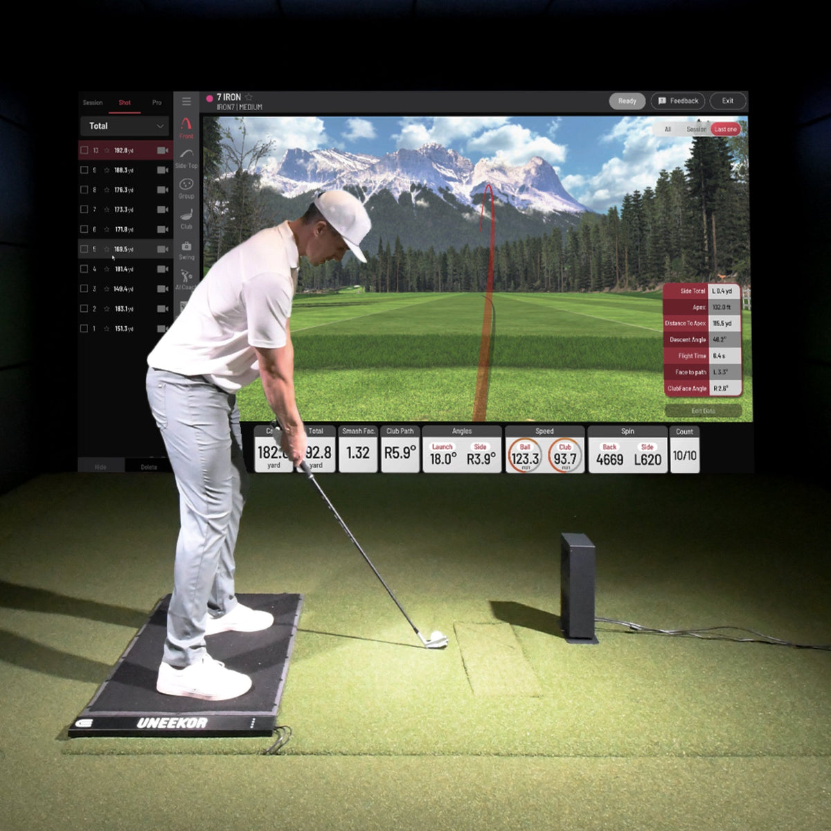 A golfer standing on a hitting mat using the Uneekor Eye Mini Lite, with the device displaying shot data and performance metrics for swing analysis