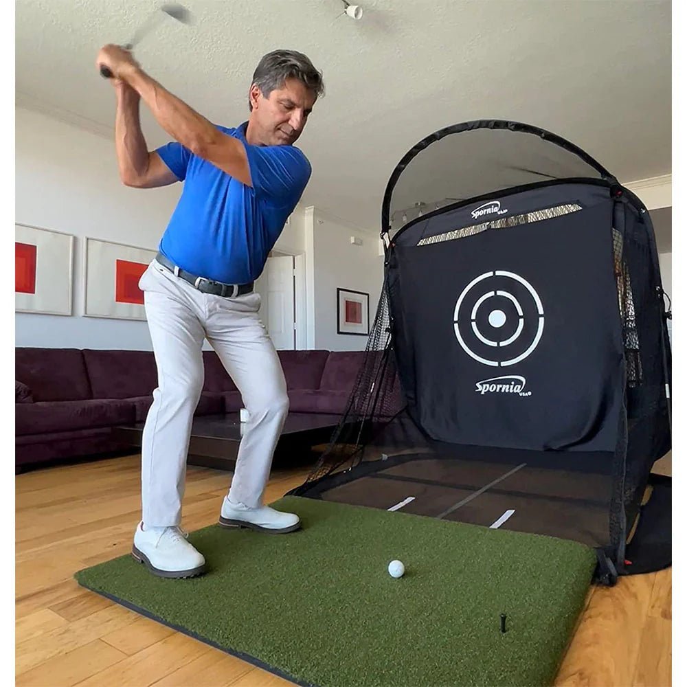 Man hitting a ball in Spornia Net in a living room.